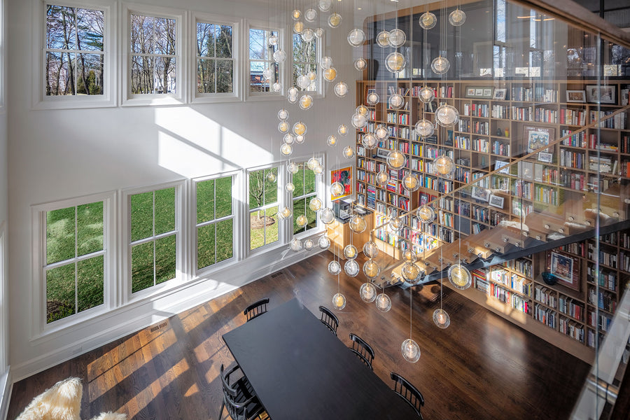 Multi-coloured Kadur orbs above a dining table in a double-height Greenwich, Connecticut library