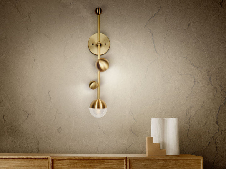 Bloom wall sconce in brass and hand-blown glass by Shakúff, mounted above a wooden credenza