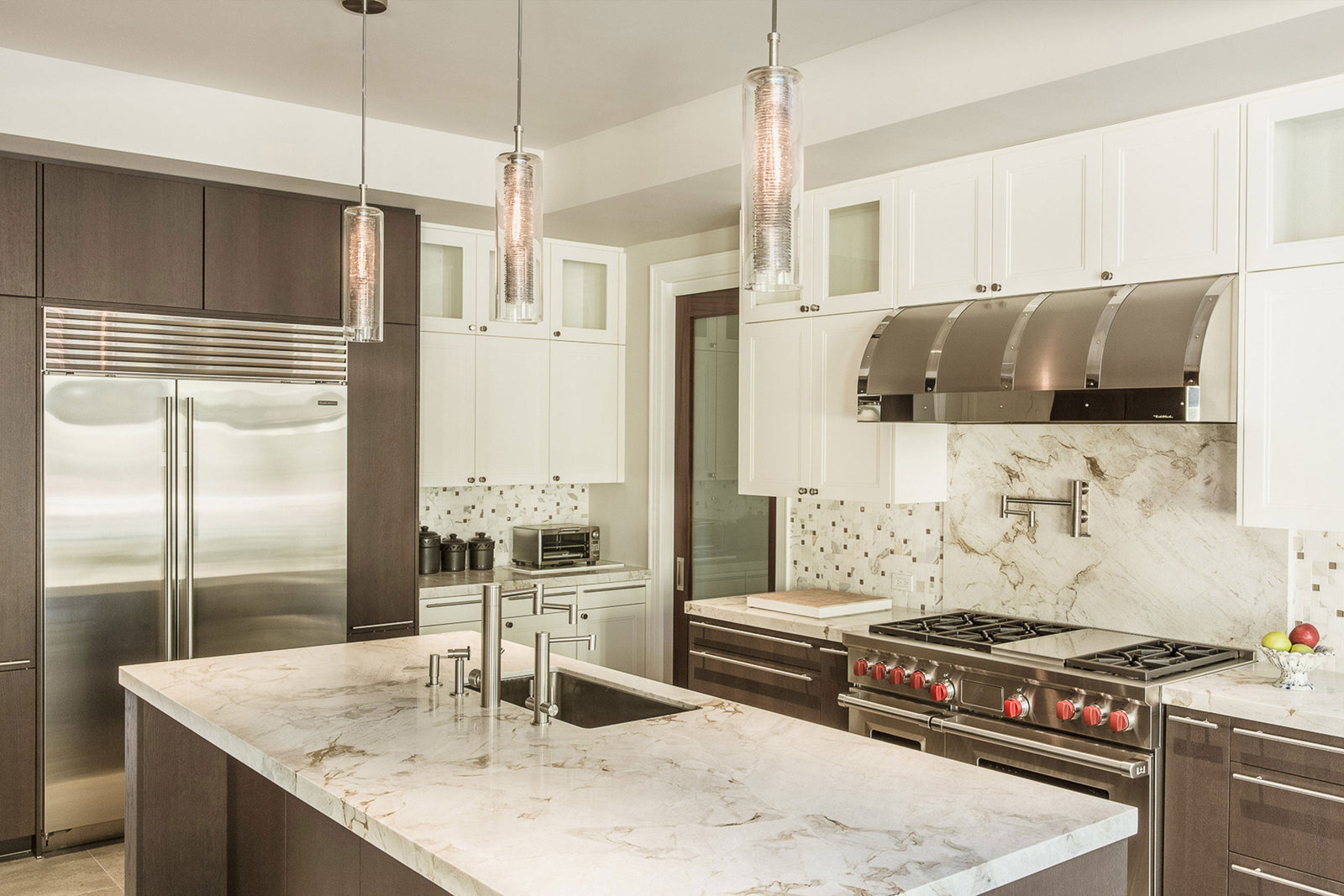 Nava hand-blown glass pendants by Shakúff above a marble kitchen island